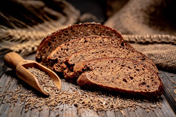 Bread rye spikelets. Freshly baked traditional bread on wooden table. - Photo, image