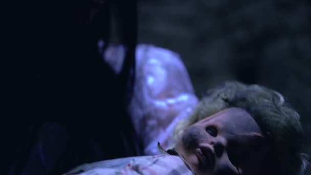 Παράφρων νεαρή γυναίκα λικνίζοντας ανατριχιαστικό μωρό κούκλα στο σκοτεινό δωμάτιο, ψυχωτική διαταραχή - Πλάνα, βίντεο