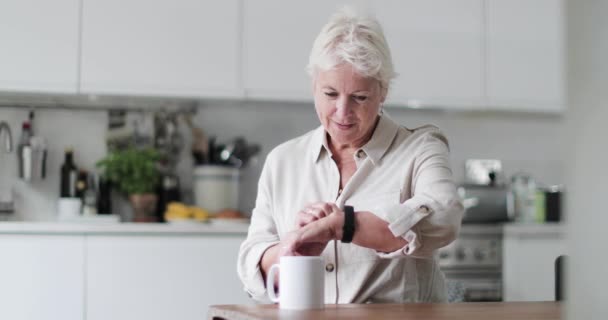 Mature adult woman looking at smartwatch smiling - Materiaali, video