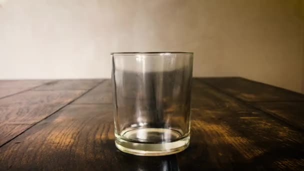 Los cubos de hielo se mueven en un vaso empañado sobre un fondo de mesa
 - Imágenes, Vídeo