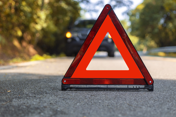 Triángulo rojo, señal roja de parada de emergencia, símbolo rojo de emergencia y parada de coche negro y aparcar en la carretera
. - Foto, Imagen