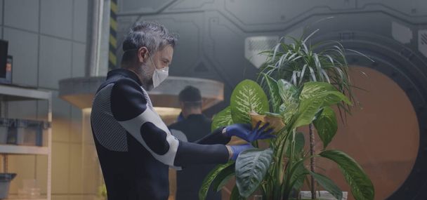 Scientist examining potted plant in Mars base - Photo, Image