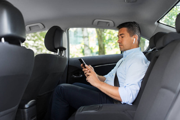 passenger with earphones and cellphone in taxi car - Photo, image