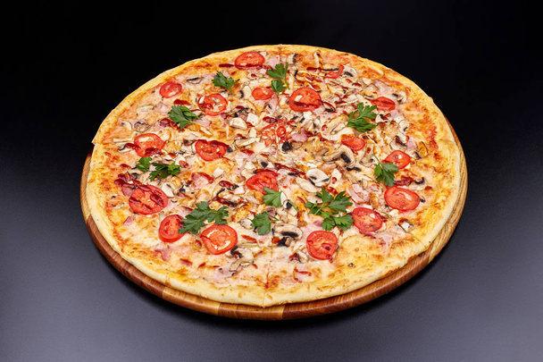 Świeża pizza z sosem BBQ na drewnianej desce do krojenia. izolowany na ciemnym tle. - Zdjęcie, obraz