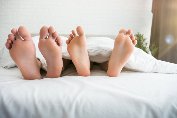 man and woman barefeet lying in the bed - Fotoğraf, Görsel