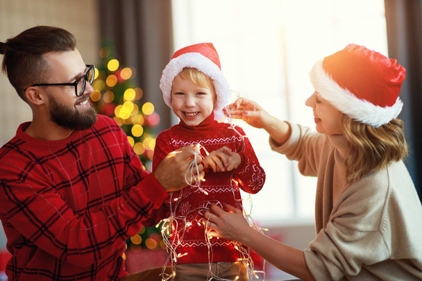 ευτυχισμένη οικογένεια διακοσμούν χριστουγεννιάτικο δέντρο, οι γονείς παίζουν με το παιδί έτσι - Φωτογραφία, εικόνα