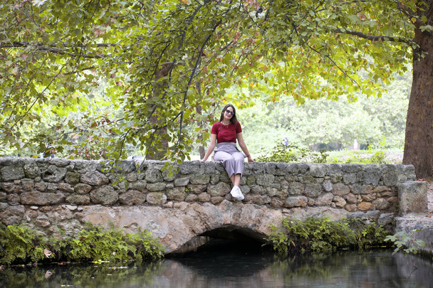 Una mujer relajada, relajándose mientras está sentada en el banco del parque natural en la temporada de otoño, España, 2019
. - Foto, imagen