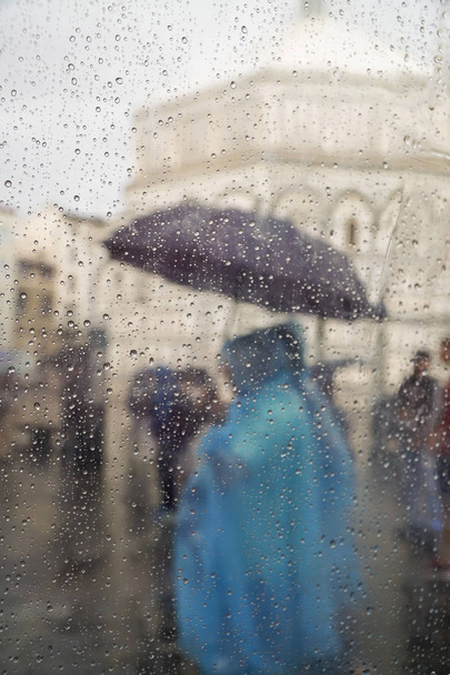 rain drops on window pane against people at street - 写真・画像
