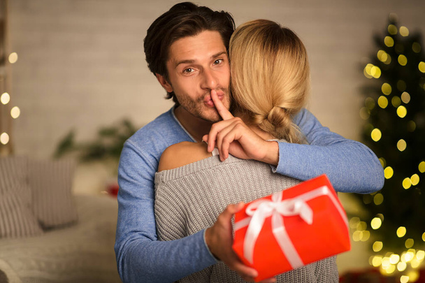 Shh Husband giving Christmas present to wife - Foto, afbeelding