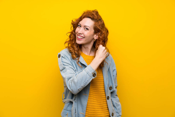 İzole sarı arka plan üzerinde Redhead kadın bir zafer kutluyor - Fotoğraf, Görsel