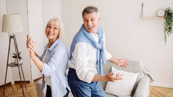 喜びに満ちた年上のカップルが家で踊り、楽しみながら - 写真・画像