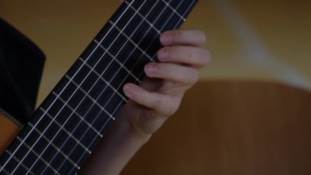 The fingers of a young man clamp the strings of a classical guitar - 映像、動画