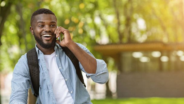 Χαρούμενος Αφροαμερικάνος που έχει ένα ευχάριστο τηλεφώνημα σε εξωτερικούς χώρους - Φωτογραφία, εικόνα