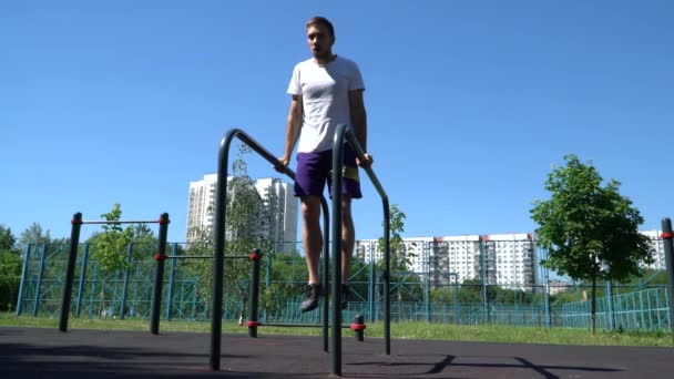 Guy doing push-UPS on uneven bars on a street Playground on a summer day - Footage, Video