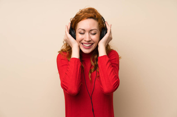 Donna rossa con maglione dolcevita che ascolta musica con cuffie
 - Foto, immagini