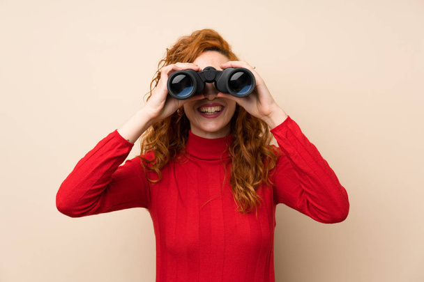 Redhead woman with turtleneck sweater with black binoculars - Photo, Image