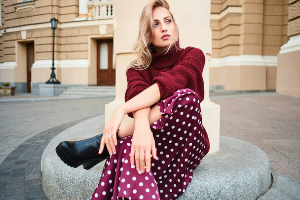 Gorgeous stylish blond girl in knitted sweater sensually looking away posing outdoor - Photo, Image