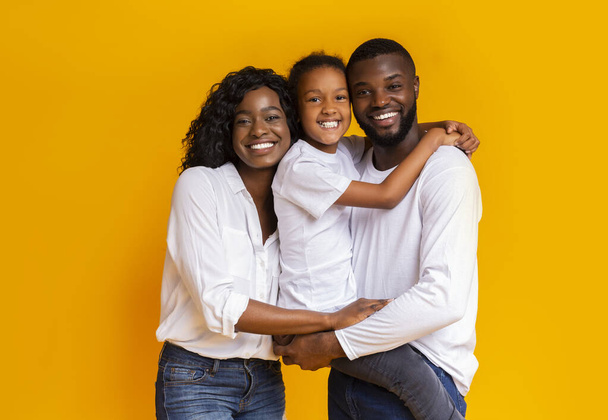 Happy Parents And Daughter Embracing Each Other Over Yellow Background - Photo, Image