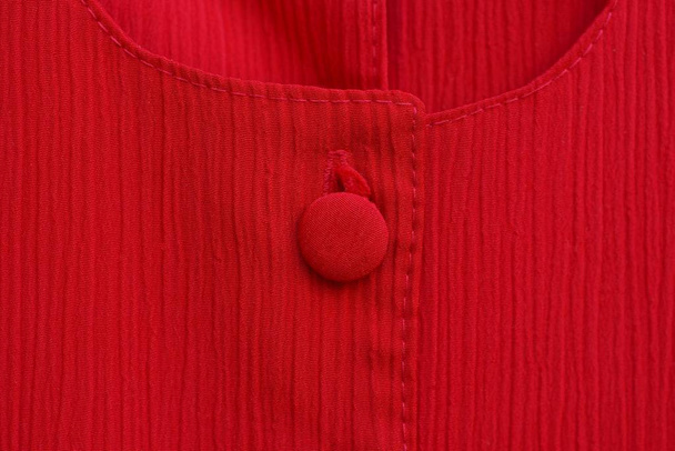 červená tkanina textura s velkým jedním tlačítkem na oblečení - Fotografie, Obrázek