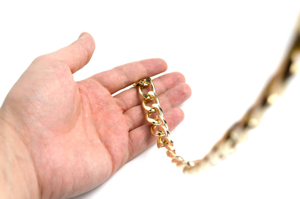 Golden chain in hands on a white background isolate - Фото, изображение