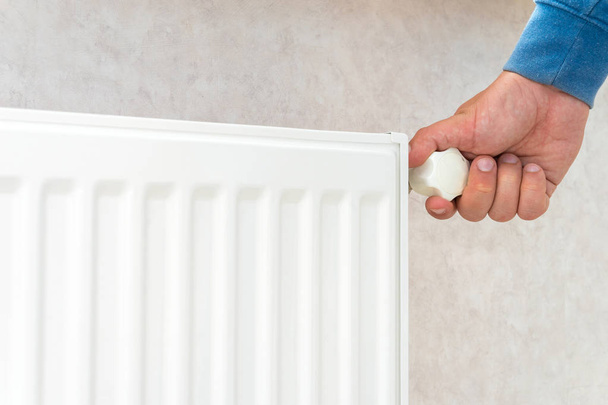 Hand adjusting the knob of heating radiator at home a cold season. - Photo, Image