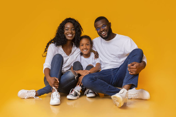 Hermosa familia afroamericana sentada en el suelo y sonriendo
 - Foto, Imagen