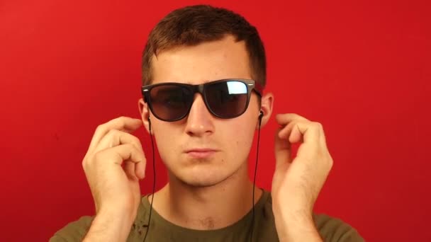 Ein Mann schüttelt mit Kopfhörern heftig den Kopf zur Musik auf rotem Hintergrund - Filmmaterial, Video