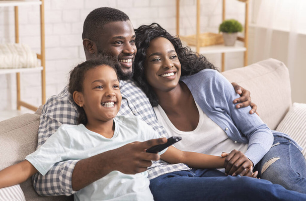 Afro-americana familia de tres sentado en sofá viendo televisión
 - Foto, imagen