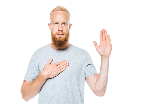 portrait d'un homme barbu sérieux prêtant serment la main en l'air et la main sur le cœur, isolé sur blanc
 - Photo, image