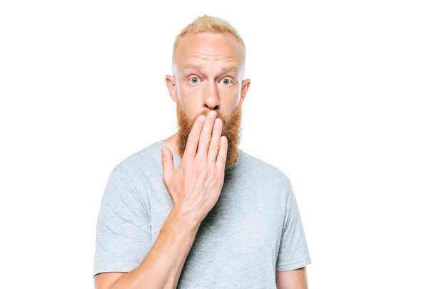 hombre sorprendido en camiseta gris que cubre la boca, aislado en blanco
 - Foto, Imagen