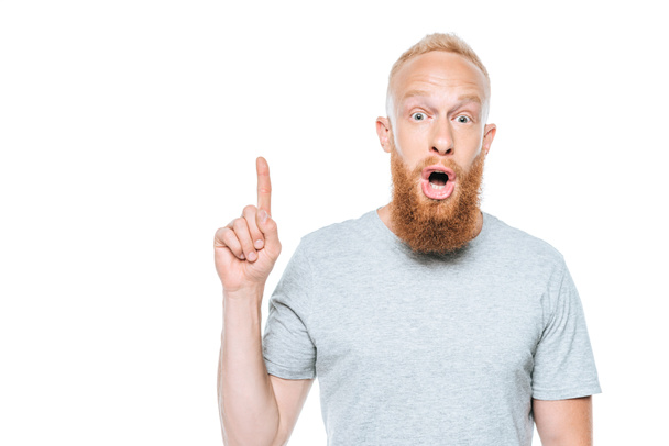 shocked bearded man in grey t-shirt pointing up, isolated on white - Foto, Imagem