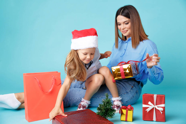 青い背景の上に孤立したプレゼントを持つ幸せな母親。クリスマスのコンセプト - 写真・画像