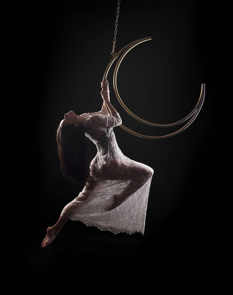 The girl, an aerial acrobat, performs on a sports equipment of the "moon" type. - 写真・画像
