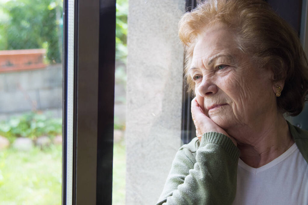 femme âgée regardant par la fenêtre coûteuse, personnes âgées
 - Photo, image