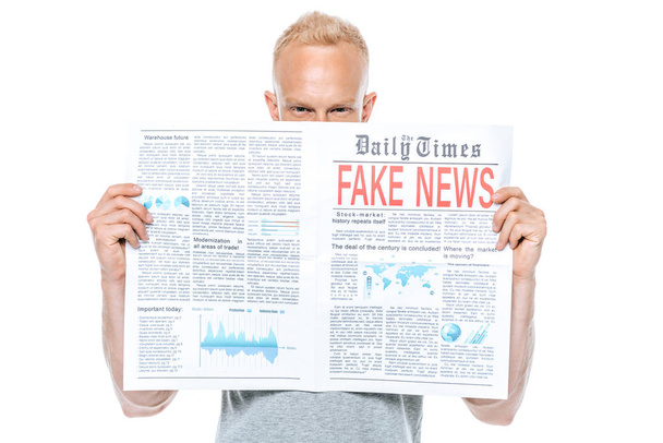 блондин, читающий газету с фальшивыми новостями, изолированный на белом
 - Фото, изображение