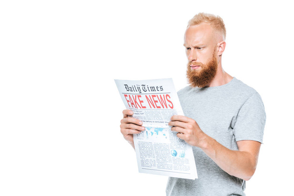handsome serious man reading newspaper with fake news, isolated on white - Fotoğraf, Görsel