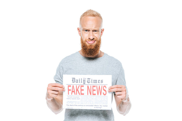 скептически настроенный бородатый мужчина показывает газету с фейковыми новостями, изолированную на белом
 - Фото, изображение
