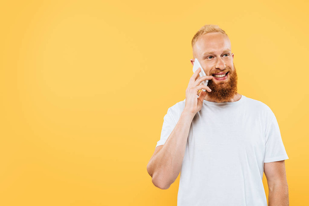 happy bearded man talking on smartphone, isolated on yellow - Фото, зображення