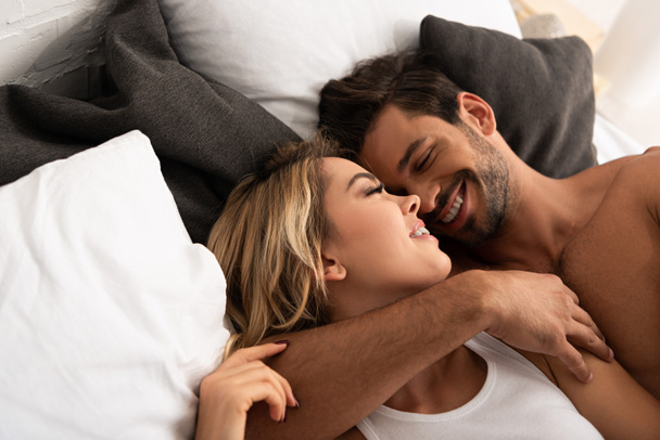 mosolygós, gyengéd pár ölelkezik az ágyban reggel  - Fotó, kép