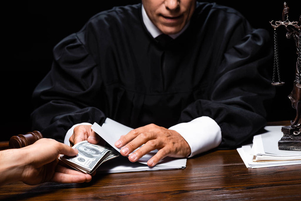 cropped view of woman giving bribe to judge isolated on black - Photo, Image