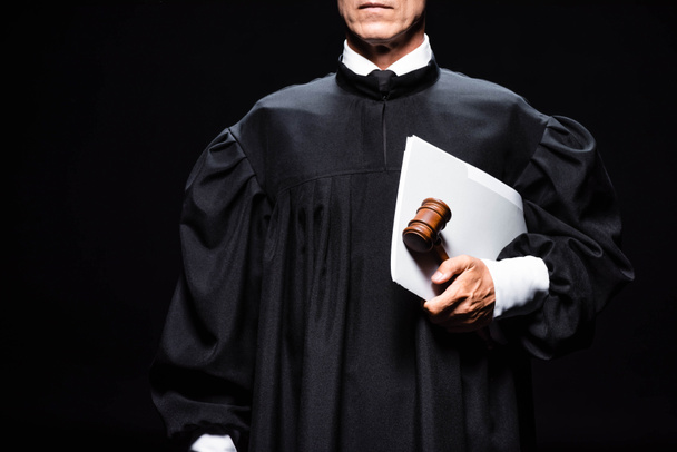 Προβολή του δικαστή με δικαστικό χιτώνα που κρατά το σφυρί και των εγγράφων που απομονώνονται στα μαύρα  - Φωτογραφία, εικόνα