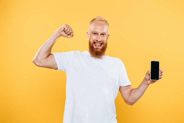 úspěšný muž zobrazující smartphone s prázdnou obrazovkou, izolovaný na žluté - Fotografie, Obrázek