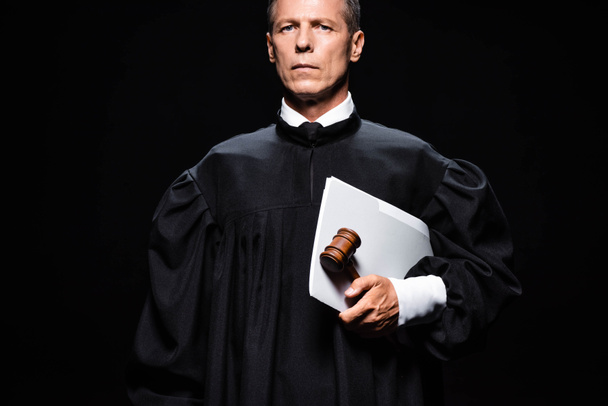 judge in judicial robe holding gavel and papers isolated on black  - 写真・画像
