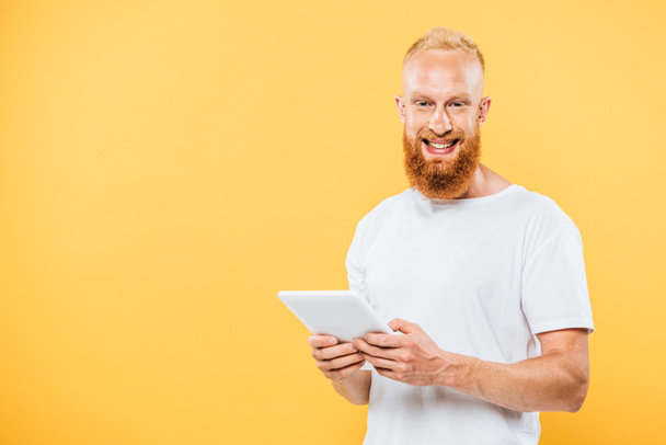 boldog szakállas férfi digitális táblagép, elszigetelt sárga - Fotó, kép