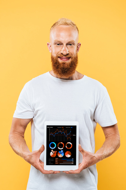 画面にインフォグラフィクス付きのデジタルタブレットを表示する髭の男黄色に隔離された - 写真・画像