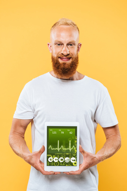 健康アプリの画面にデジタルタブレットを表示する髭の男黄色に隔離された - 写真・画像