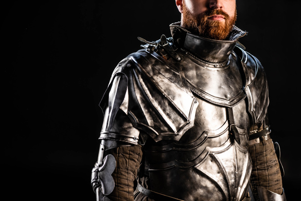 cropped view of knight in armor isolated on black - Foto, afbeelding