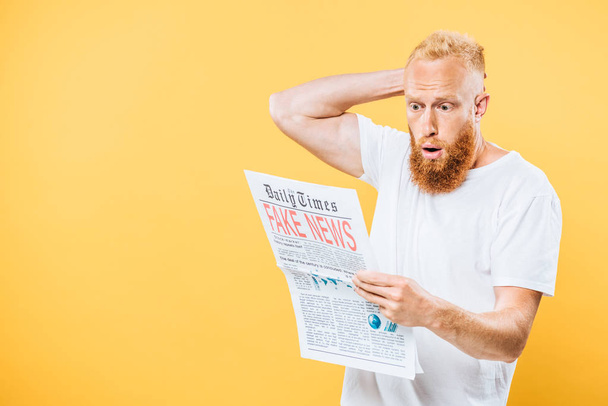 shocked man reading newspaper with fake news, isolated on yellow - Foto, imagen