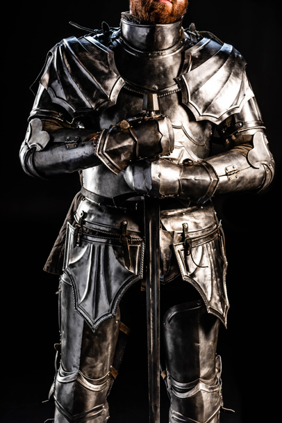 vista recortada de caballero en la armadura que sostiene la espada aislado en negro
  - Foto, imagen
