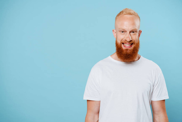 portrait of handsome smiling bearded man in white t-shirt, isolated on blue  - Foto, imagen